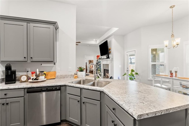 kitchen with a peninsula, gray cabinets, a sink, light countertops, and stainless steel dishwasher