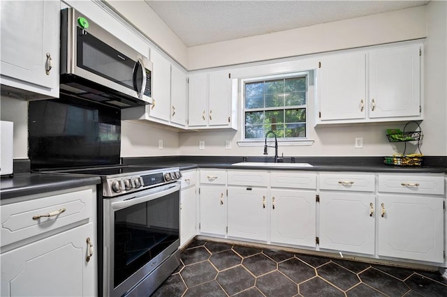 7072 Forest Glenn Ct, Irvington, AL 36544 - kitchen featuring appliances with stainless steel finishes, dark countertops, white cabinetry, and a textured ceiling