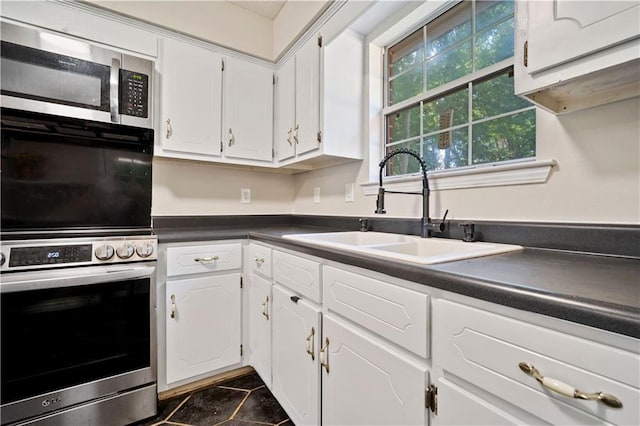 7072 Forest Glenn Ct, Irvington, AL 36544 - kitchen with stainless steel appliances, dark countertops, white cabinetry, and dark tile patterned floors