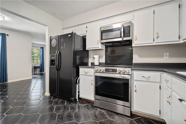7072 Forest Glenn Ct, Irvington, AL 36544 - kitchen with stainless steel appliances, a textured ceiling, dark countertops, white cabinets, and dark tile patterned floors