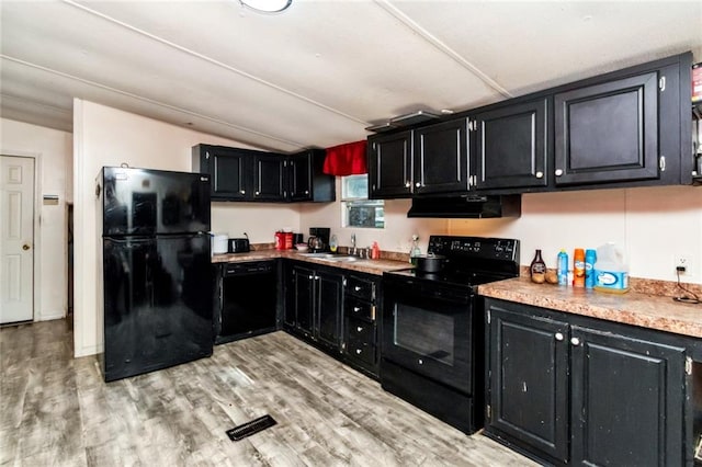 kitchen with black appliances, sink, light wood-type flooring, and vaulted ceiling