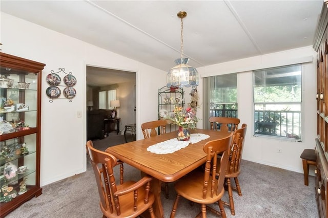 carpeted dining space featuring vaulted ceiling