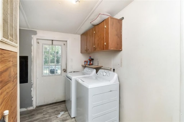 clothes washing area with light hardwood / wood-style floors, cabinets, and separate washer and dryer