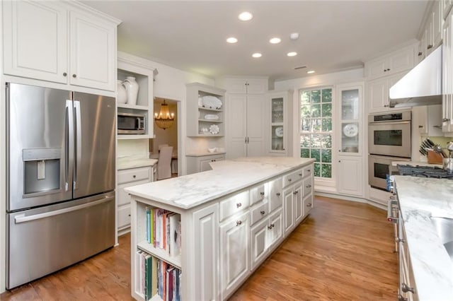 kitchen with appliances with stainless steel finishes, white cabinetry, and a kitchen island