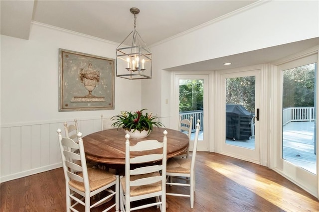 dining space with dark wood-type flooring, an inviting chandelier, and crown molding