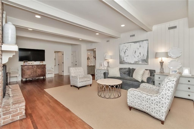 living room with a fireplace, beam ceiling, hardwood / wood-style flooring, and wooden walls