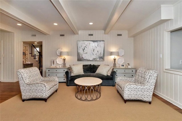 living area with wood walls, beam ceiling, and carpet flooring