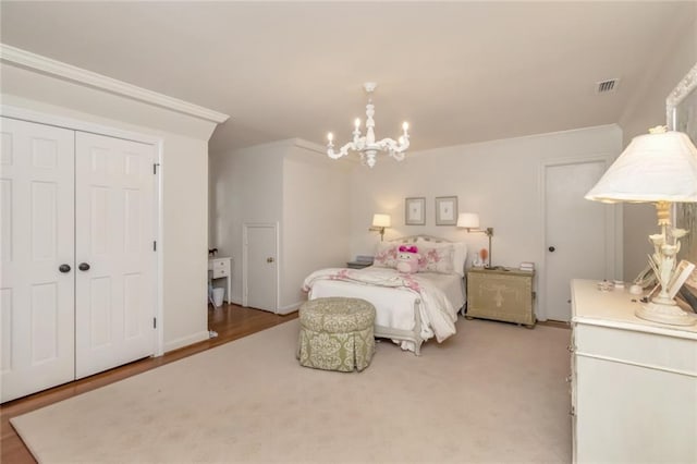 carpeted bedroom with a closet, a notable chandelier, and ornamental molding