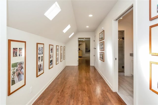 hallway with wood-type flooring and lofted ceiling with skylight