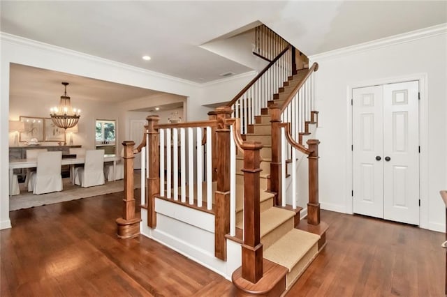 staircase featuring ornamental molding, a chandelier, and hardwood / wood-style flooring