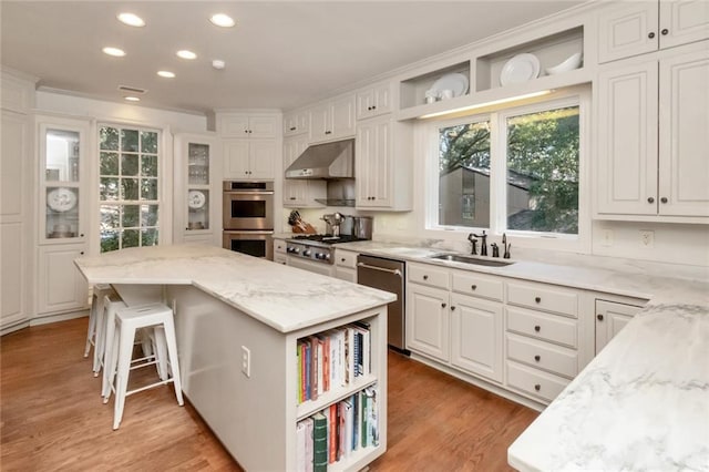 kitchen featuring light hardwood / wood-style flooring, a kitchen breakfast bar, a center island, appliances with stainless steel finishes, and white cabinets