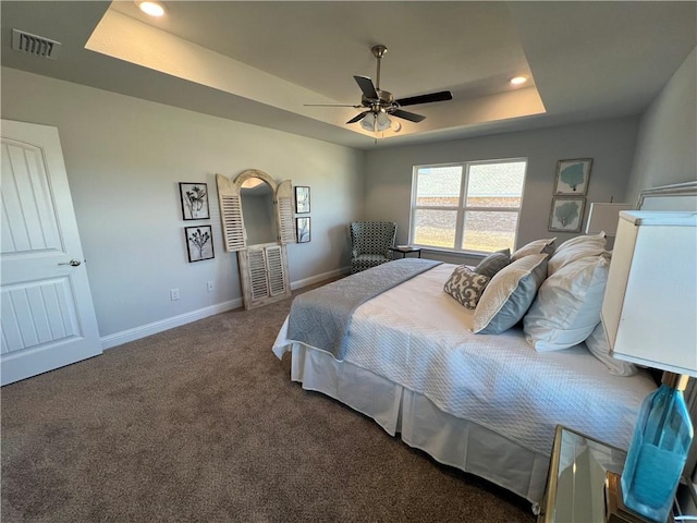 carpeted bedroom featuring ceiling fan and a raised ceiling