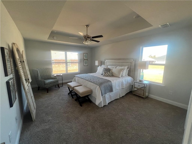 carpeted bedroom with ceiling fan and a raised ceiling