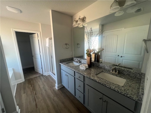 bathroom with hardwood / wood-style flooring, a textured ceiling, a shower with shower door, and vanity