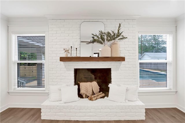 room details with ceiling fan, wood-type flooring, ornamental molding, and a brick fireplace