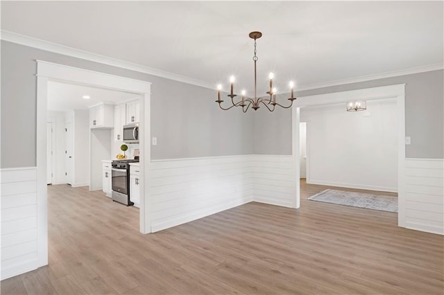 unfurnished dining area with ornamental molding, a notable chandelier, and light hardwood / wood-style floors