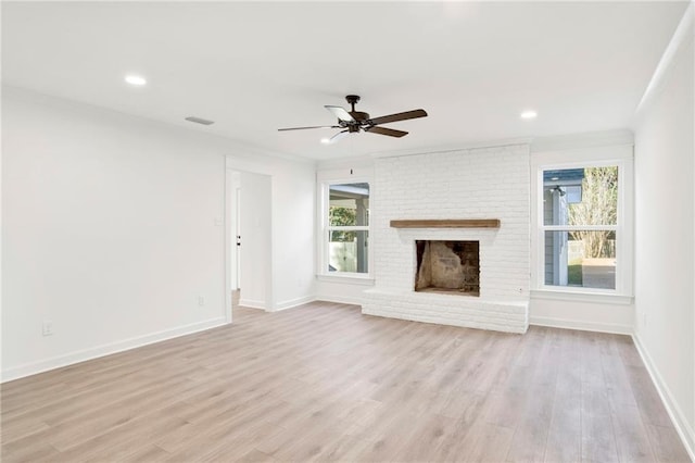 unfurnished living room with a brick fireplace, ceiling fan, and light wood-type flooring