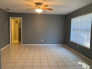 spare room with ceiling fan and light tile patterned floors