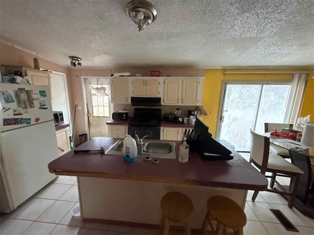 kitchen featuring sink, light tile patterned floors, white fridge, range hood, and stove