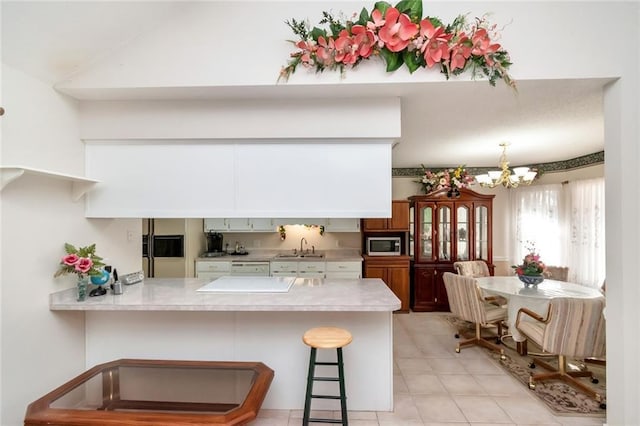 kitchen with a kitchen breakfast bar, sink, kitchen peninsula, and a notable chandelier