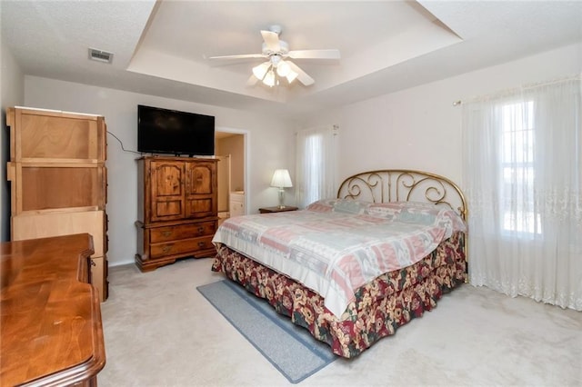 carpeted bedroom with ceiling fan and a tray ceiling