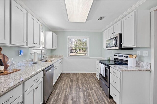 kitchen featuring sink, dark wood-type flooring, appliances with stainless steel finishes, white cabinets, and ornamental molding