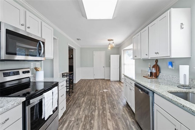 kitchen featuring appliances with stainless steel finishes, dark hardwood / wood-style floors, white cabinetry, and crown molding