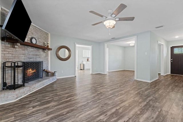 unfurnished living room featuring dark hardwood / wood-style floors, ceiling fan, and a brick fireplace