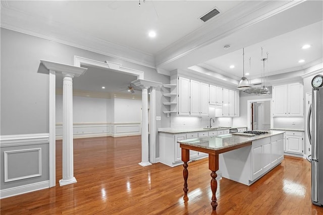 kitchen featuring a kitchen breakfast bar, light hardwood / wood-style flooring, a center island, white cabinetry, and hanging light fixtures