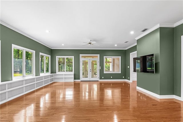 unfurnished living room featuring wood-type flooring, ornamental molding, ceiling fan, and french doors