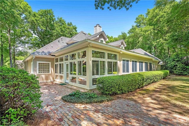 rear view of house featuring a sunroom and a patio area