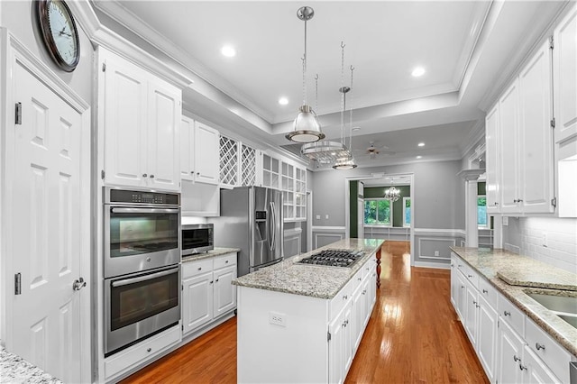 kitchen with stainless steel appliances, pendant lighting, white cabinetry, light hardwood / wood-style floors, and a kitchen island