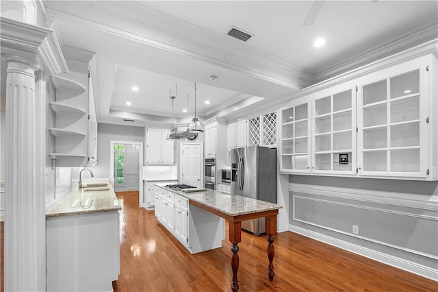 kitchen featuring stainless steel appliances, sink, light hardwood / wood-style flooring, white cabinetry, and hanging light fixtures