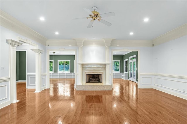 unfurnished living room featuring light hardwood / wood-style flooring, a high end fireplace, decorative columns, and ceiling fan