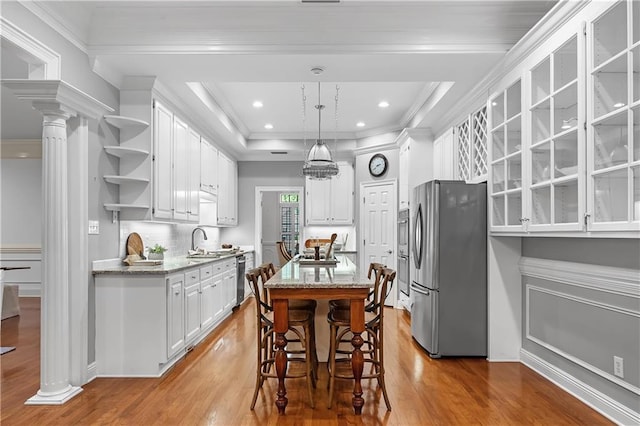 kitchen featuring light stone counters, stainless steel appliances, crown molding, hardwood / wood-style flooring, and white cabinets