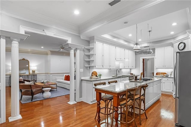 kitchen featuring white cabinetry, appliances with stainless steel finishes, a center island, and ornate columns