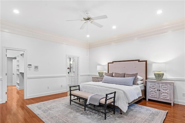 bedroom featuring hardwood / wood-style floors, ensuite bathroom, ceiling fan, and crown molding