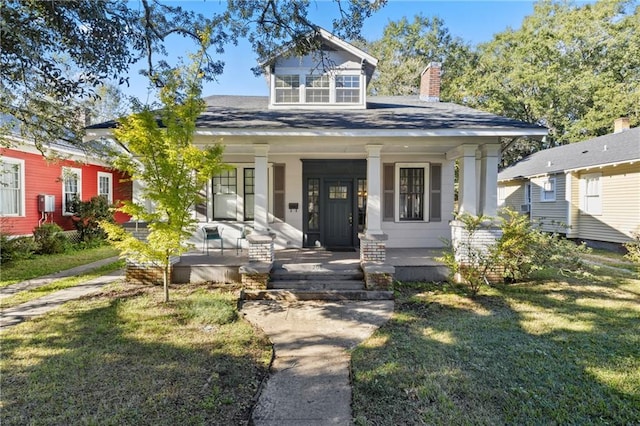 bungalow-style home featuring covered porch and a front yard