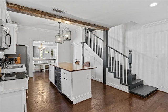 kitchen featuring beamed ceiling, a center island, white cabinetry, and an inviting chandelier