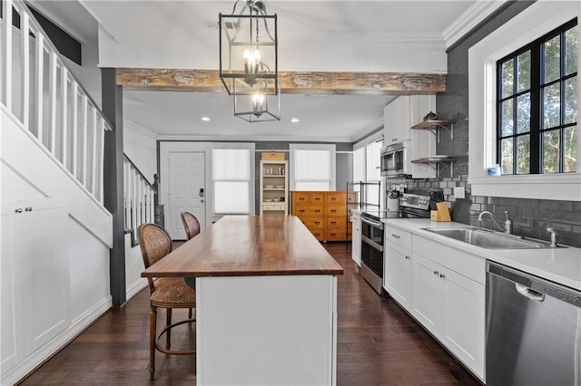 kitchen featuring pendant lighting, a kitchen island, beam ceiling, a kitchen bar, and stainless steel appliances