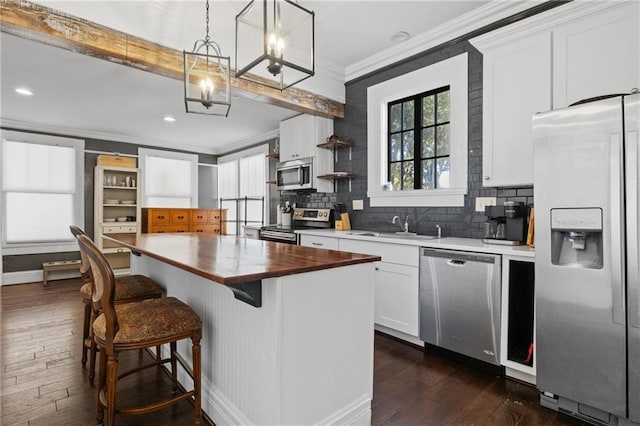 kitchen featuring butcher block countertops, white cabinets, pendant lighting, and appliances with stainless steel finishes