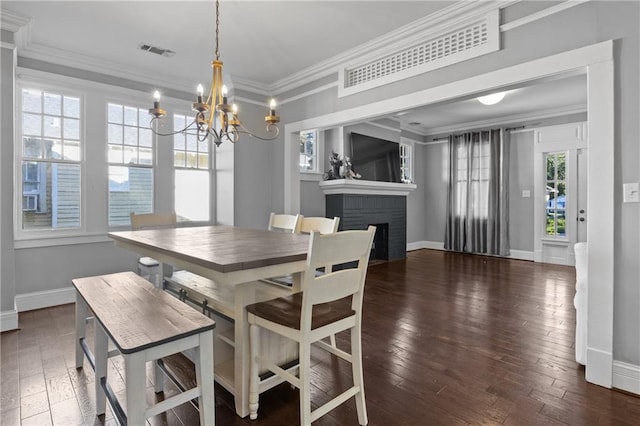 dining area with a chandelier, dark wood-type flooring, a brick fireplace, and ornamental molding