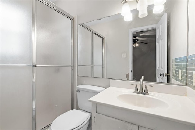 bathroom with ceiling fan, vanity, a shower with door, and toilet