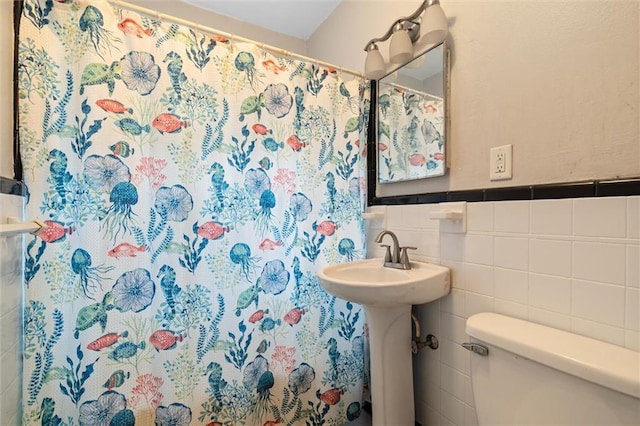 bathroom featuring toilet, tile walls, sink, and curtained shower