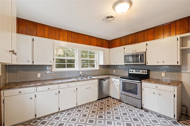 kitchen featuring appliances with stainless steel finishes, white cabinets, tasteful backsplash, and sink