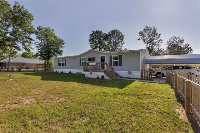 rear view of house with a lawn, fence, and a carport