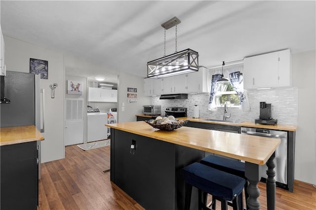 kitchen with independent washer and dryer, appliances with stainless steel finishes, a sink, wood counters, and white cabinetry