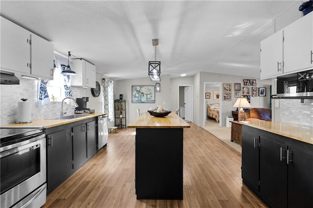 kitchen featuring a center island, dark cabinets, a sink, appliances with stainless steel finishes, and backsplash