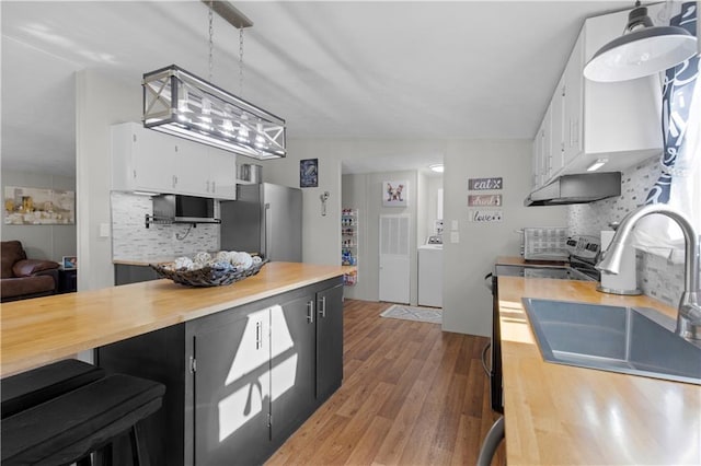 kitchen featuring freestanding refrigerator, butcher block counters, light wood-type flooring, white cabinetry, and backsplash