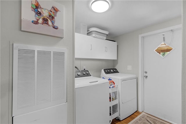 washroom with light wood-style floors, a heating unit, cabinet space, and washing machine and dryer